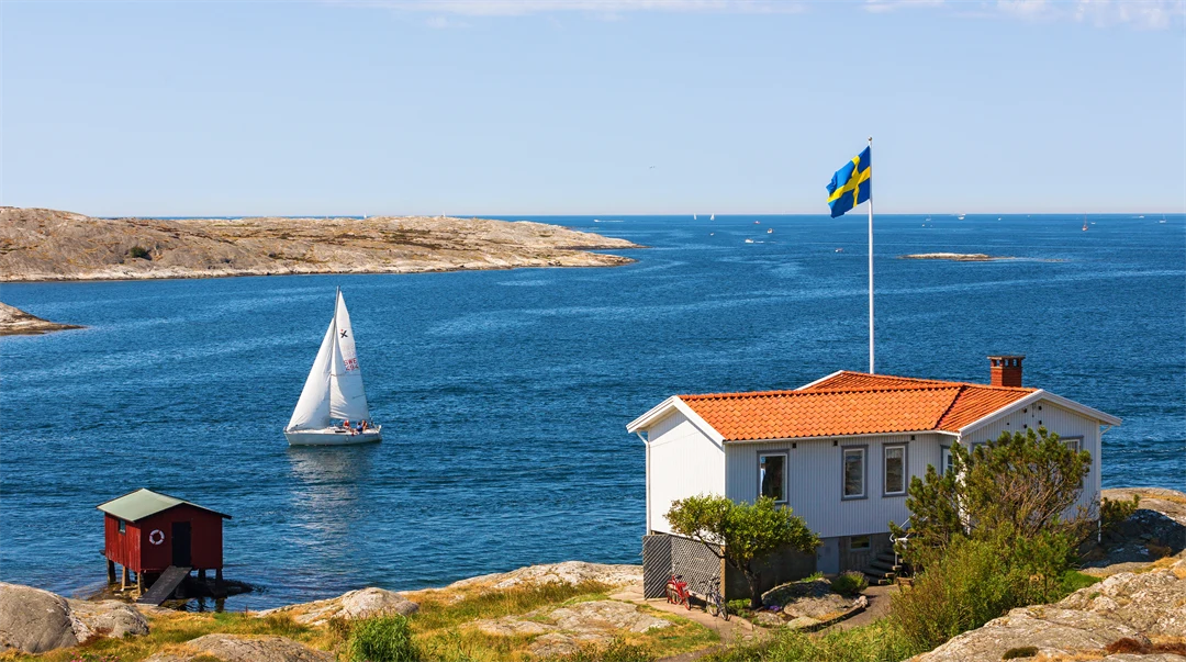 En vy från en skärgård i Sverige med en stuga och svenska flaggan