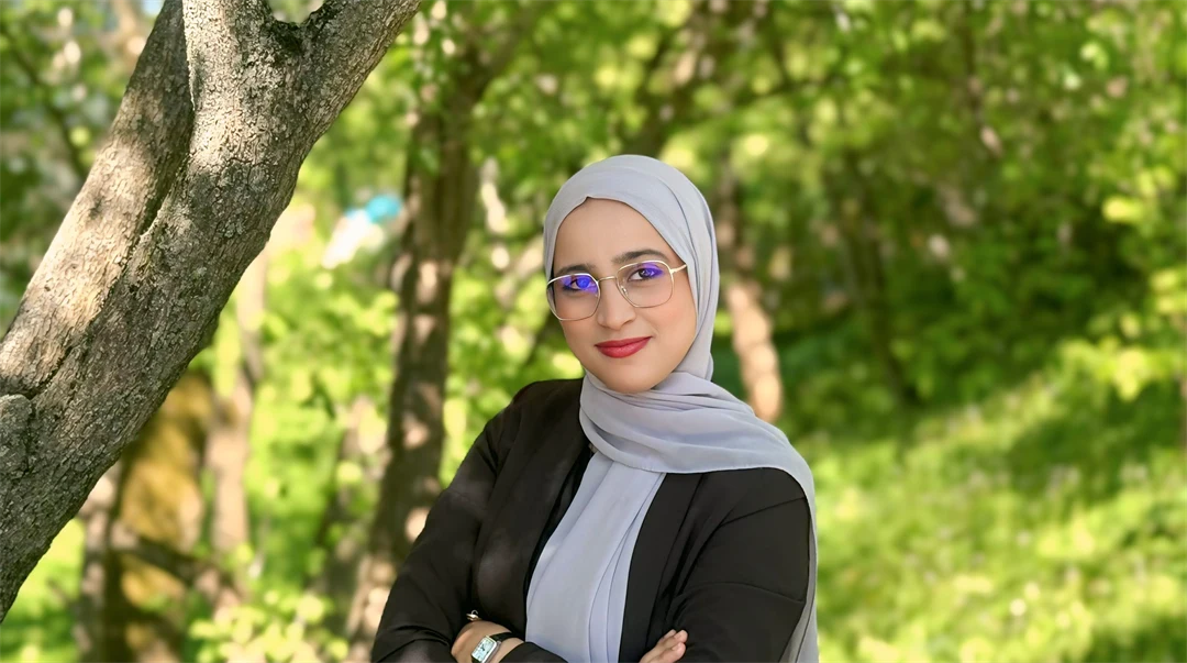 En kvinna med glasögon, en grå slöja och en svart tröja