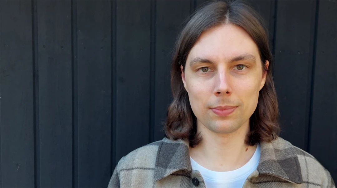 Ett porträttfoto av en man med axellångt brun hår