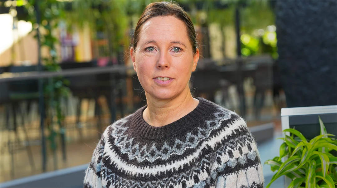 Kvinna med brunt uppsatt hår och stickad kofta.