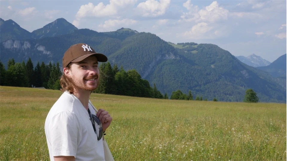 John Lind, doktorand i Alpmema-projektet, ståendes framför berg i alplandskap