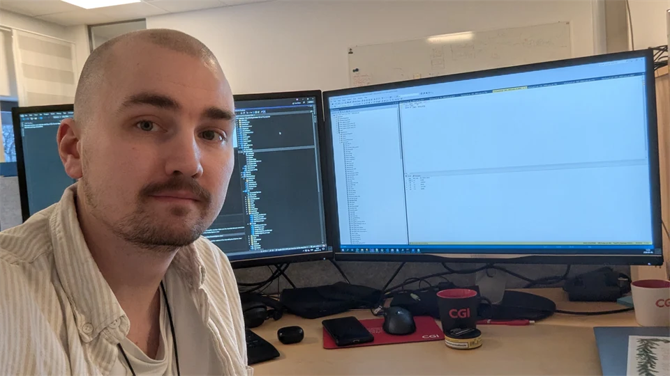 En man sitter framför två dataskärmar.