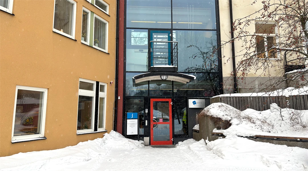 Husfasad i två olika färger, ett glasparti och en röd dörr.