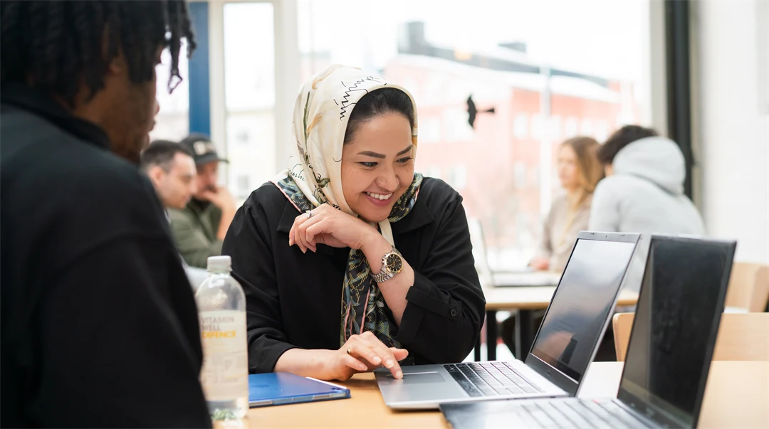 A women sitting at a laptop and smiles. 