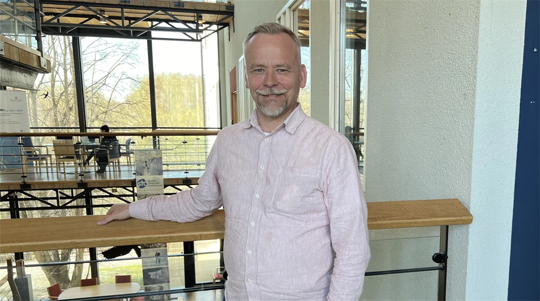 En man i en ljus skjorta står i en ljusgård.