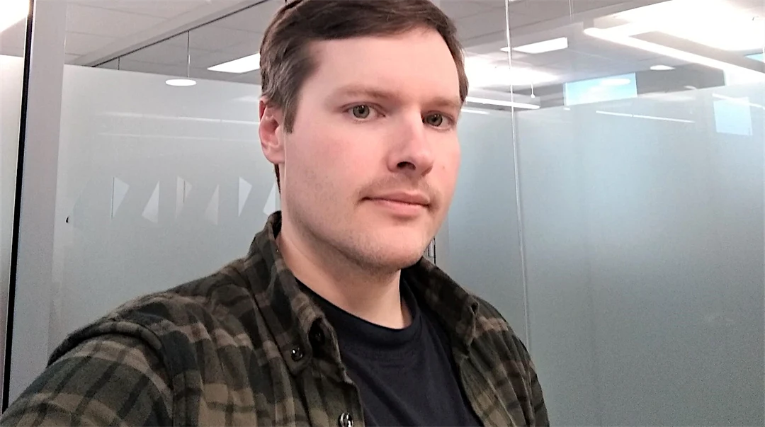 Porträtt av en kille med mörkt kort hår och klädd i rutig skjorta