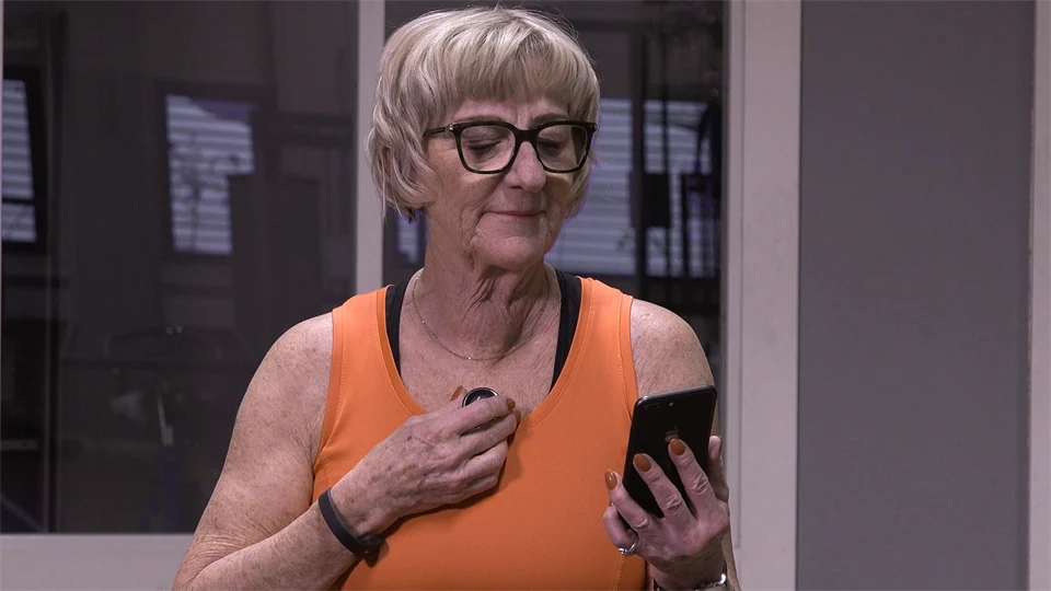 A woman at the gym records the sound of her heart via her mobile phone. 