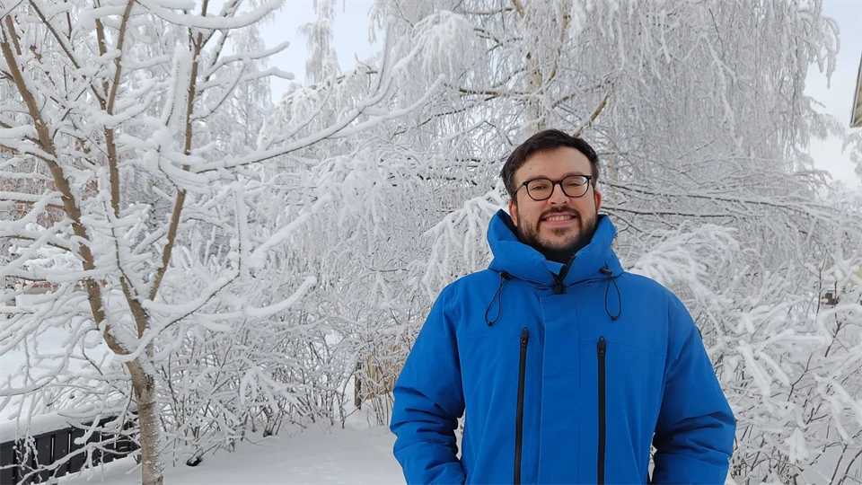 A man with a blue jacket stand in a snowy landscape
