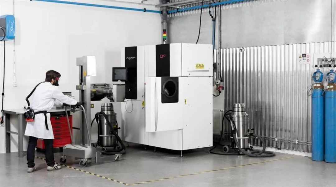 Bild från en industrilokal, en person i vit rock vid en maskin