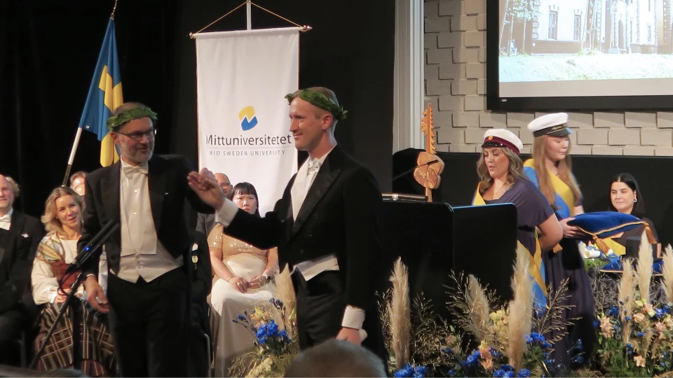 Axel Eriksson står på scenen under den akademiska högtiden och tar emot sin ring samt krans