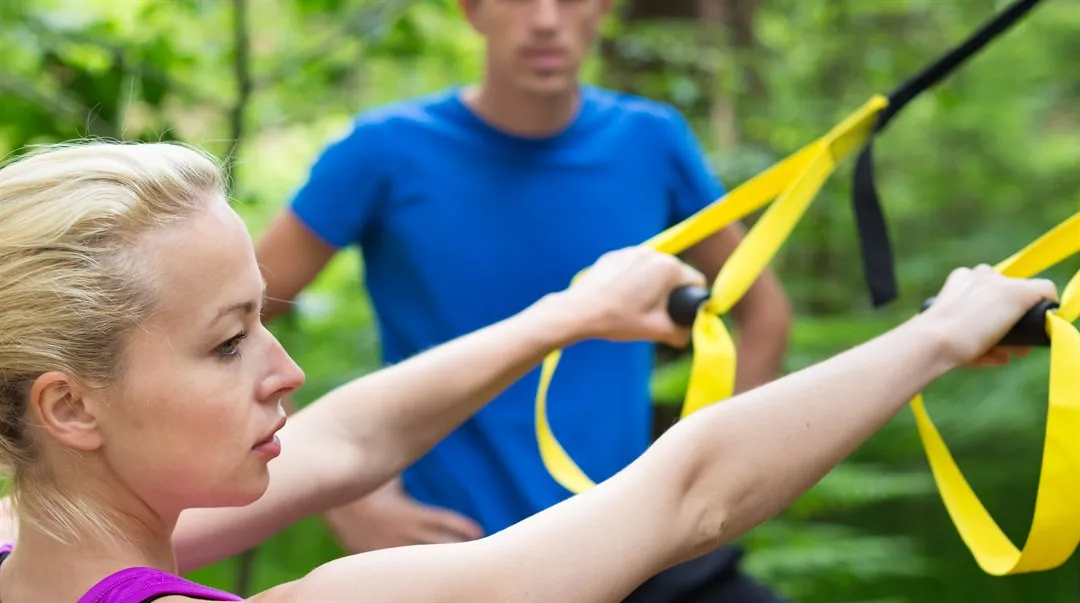 Kvinna och man tränar på ett utegym i naturen
