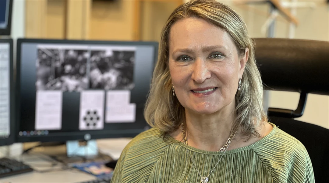 En kvinna med en dataskärm i bakgrunden.