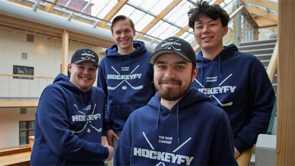 Fyra män står tillsammans, de har blå tröjor på sig.