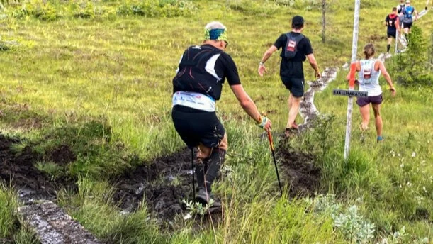 Människor som springer utomhus längs en lerig led i fjällmiljö 