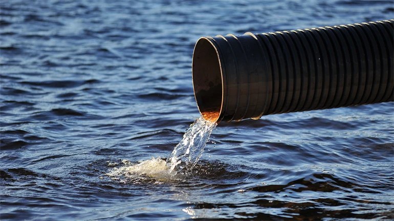 Water flowing out of a sewer pipe into a lake.