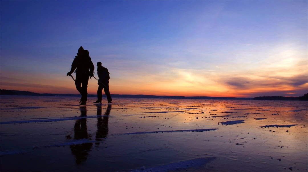 två personer åker skridskor i vacker solnedgång