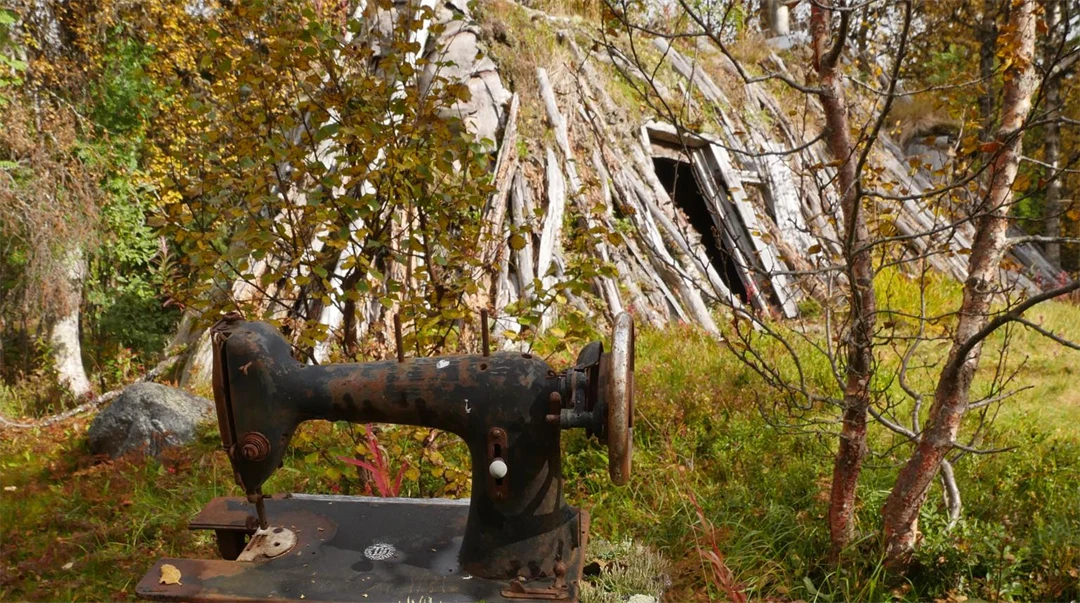 En gammal symaskin utanför en förfallande kåta.