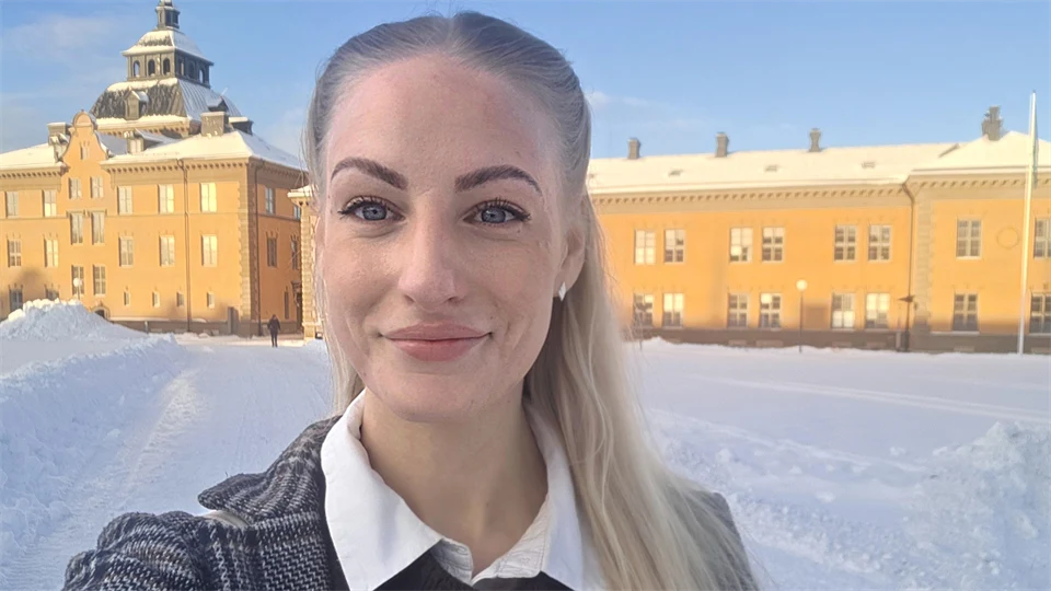 Utomhusbild av kvinna som står med byggnad i bakgrunden.