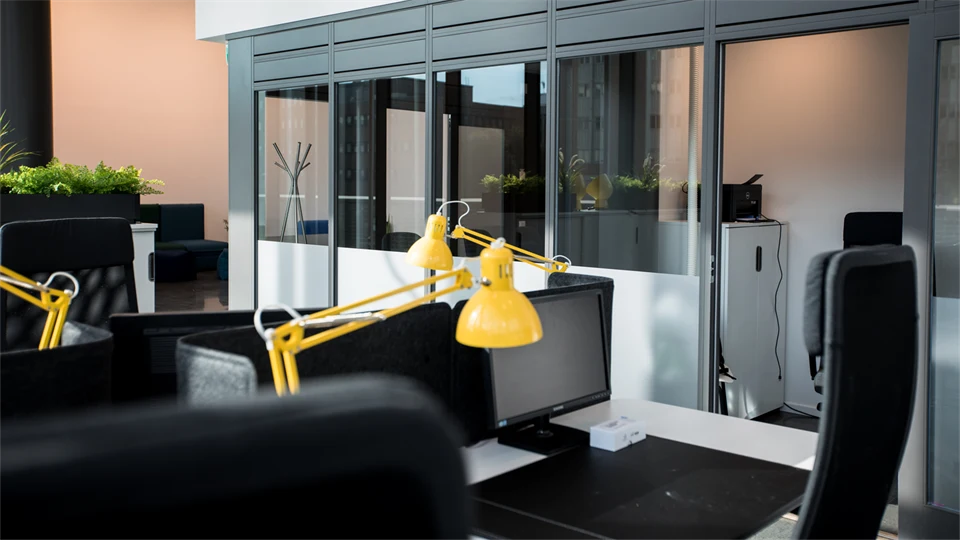 Open office space with black chairs, yellow desk lamps and light walls.