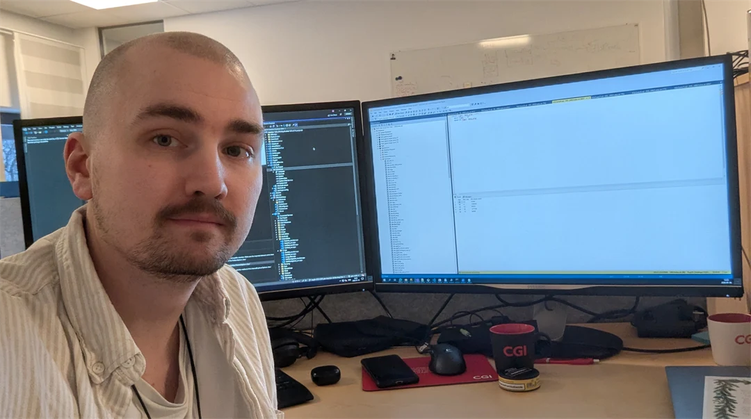 En man sitter framför två dataskärmar.