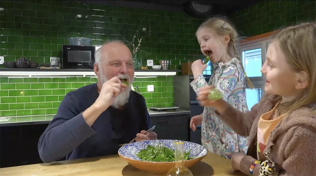 En man och två barn äter sallad