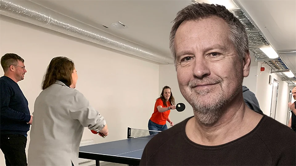 folk spelar pingis i bakgrunden, i förgrunden en man som ler