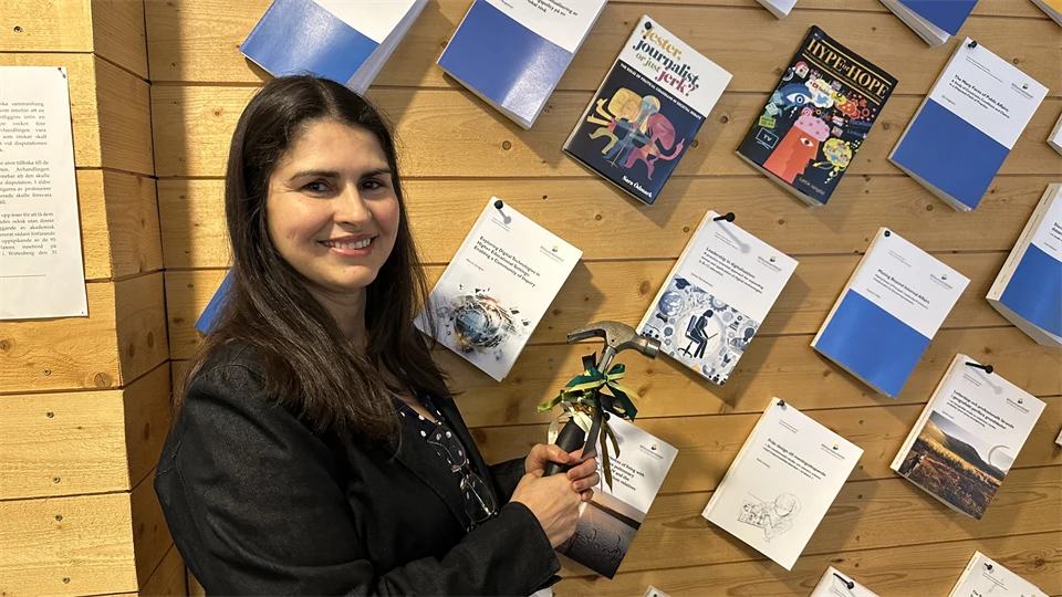 A woman in dark hair nail up her thesis