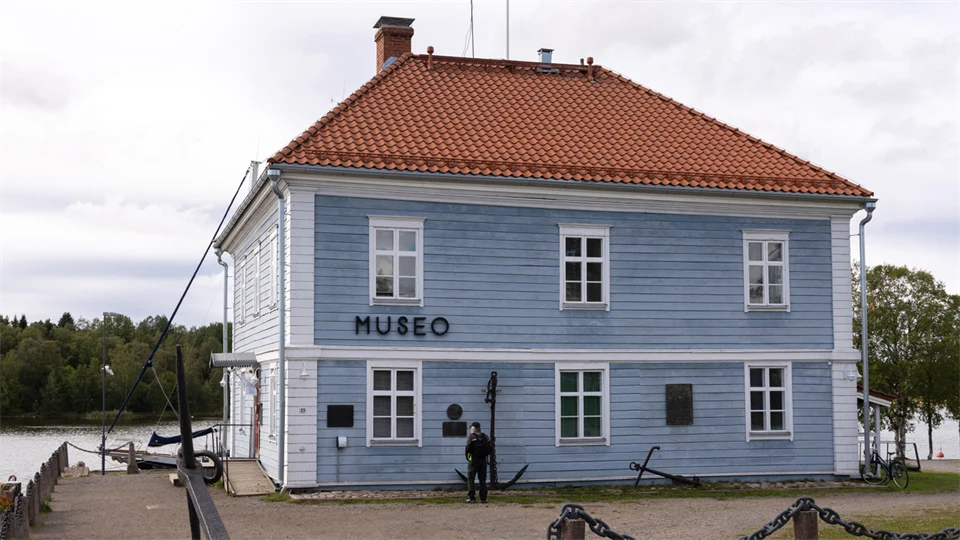 Ljust blått trähus med vita knutar och tegeltak. På fasaden står Museo. 