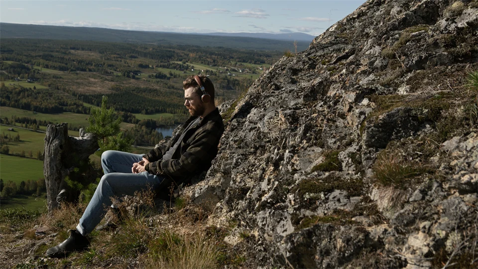 Man lutar sig mot bergvägg och blickar ut över öppet landskap