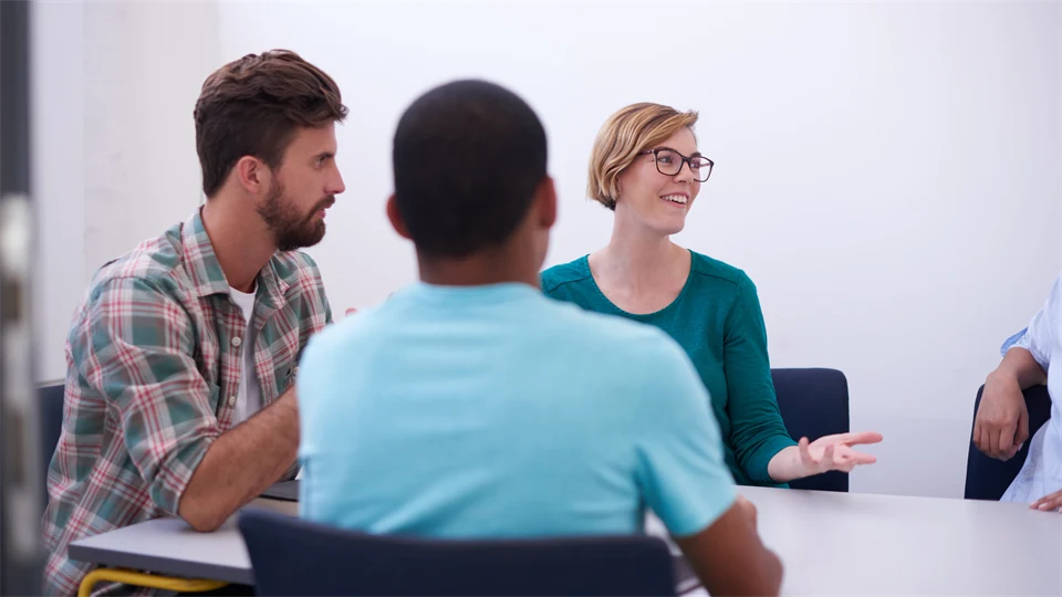 Tre personer, en kvinna och två män, sitter i ett informellt möte.