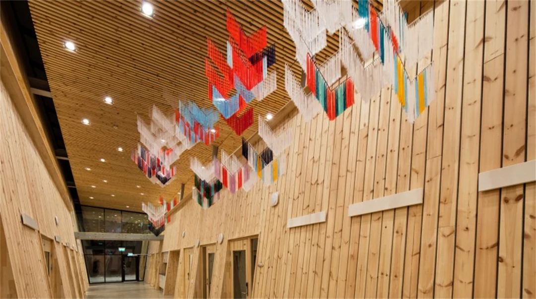 Konstverk av trådar i formen av samiska sidensjalar hänger från taket i träbyggnad av modern arkitektur