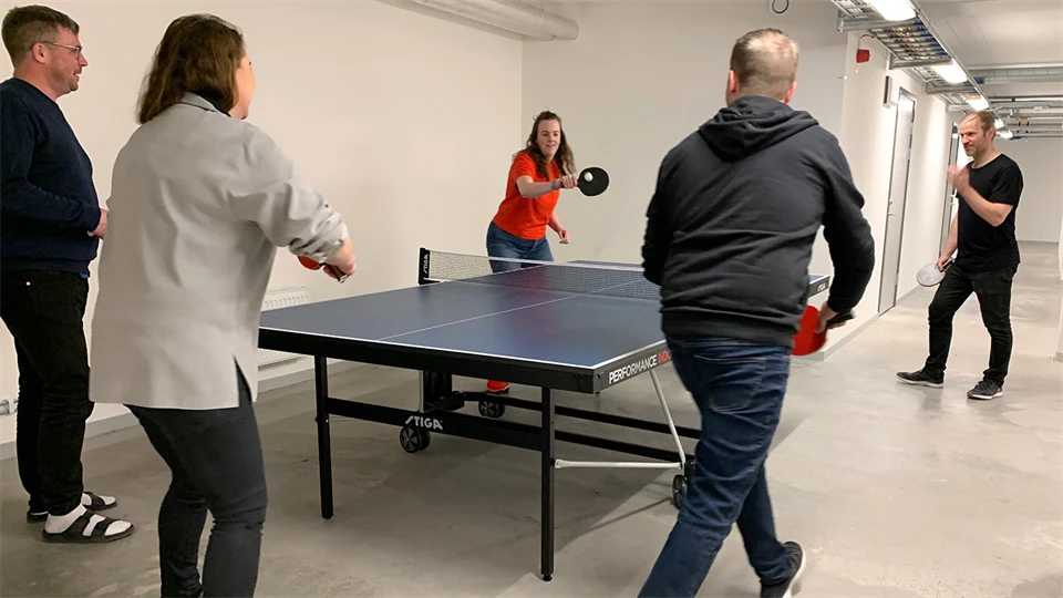Flera personer spelar rundpingis i källarlokal.