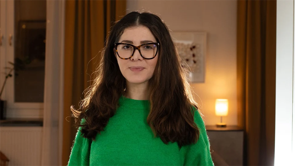 Kvinna i grön tröja, glasögon och långt hår.