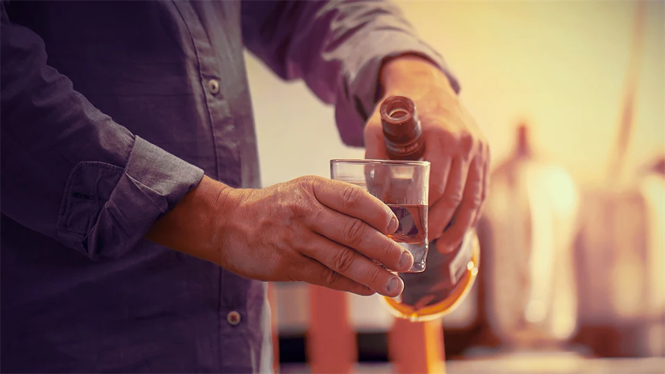 Elderly man pouring alcohol into a glass.