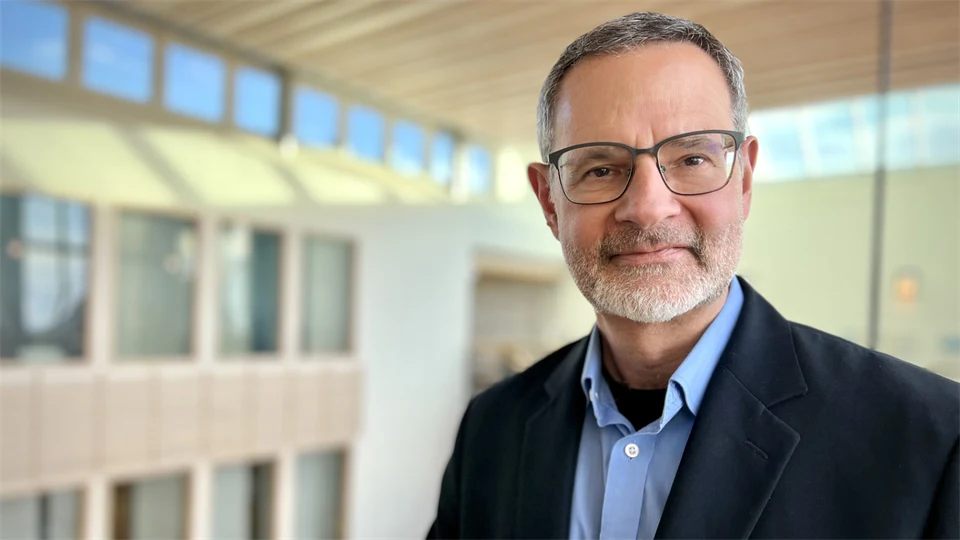 A man in a blue jacket, shirt and glasses