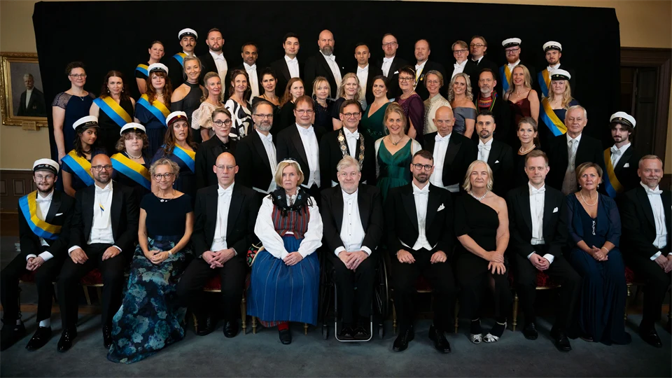 Gruppbild med högtidsklädda personer som sitter och står.