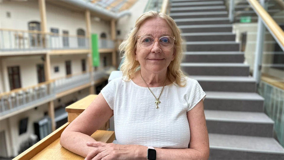 Porträttfoto av en blond kvinna ståendes framför en trappa
