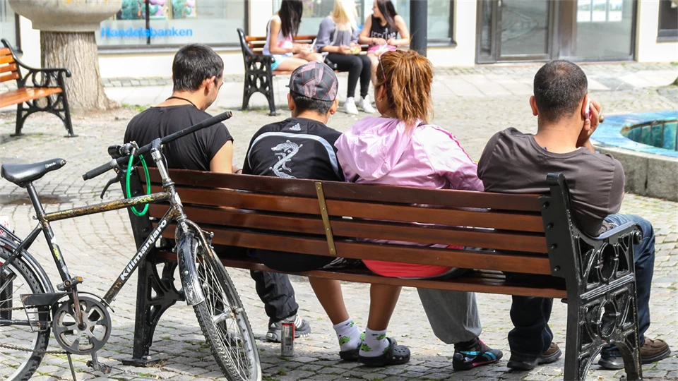 Fyra ungdomar på en parkbänk på ett torg