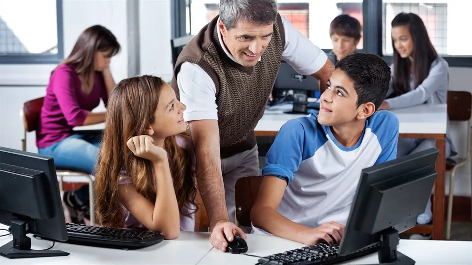  Manlig lärare använder dator medan elever tittar på honom i klassrummet