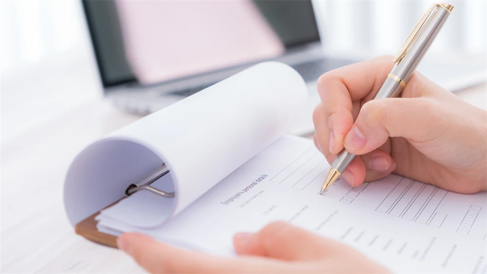 Hand with pen over assessment form.