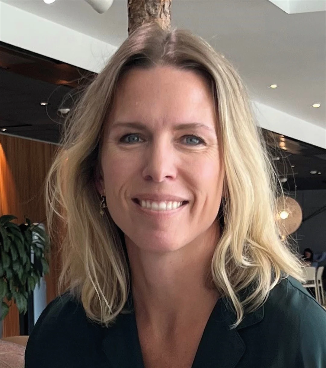 en kvinna ler och tittar in i kameran