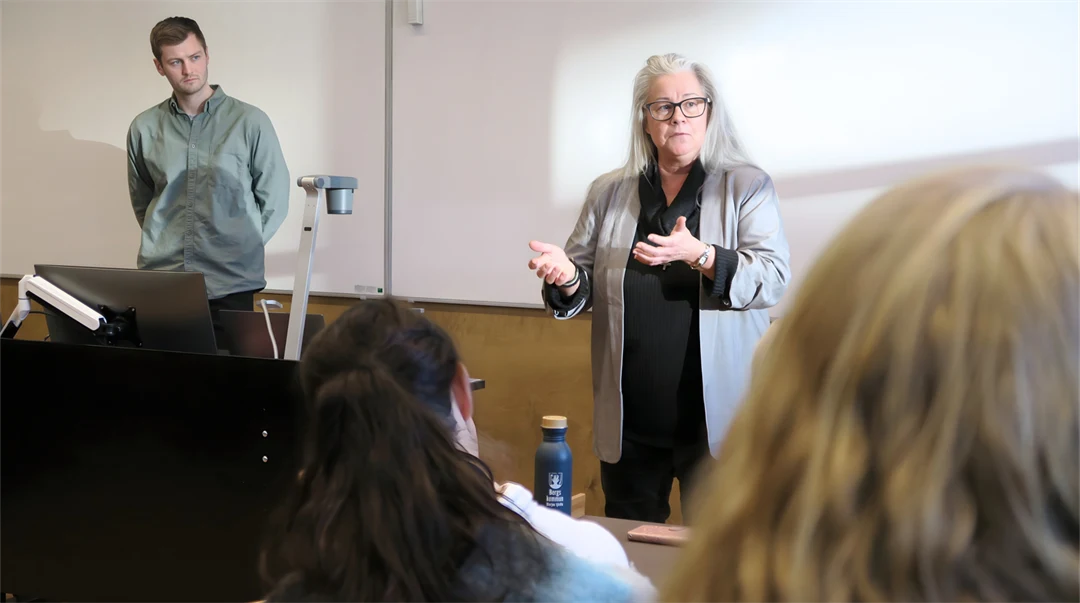 Ung man och kvinna i övre medelåldern håller en föreläsning i en lektionssal