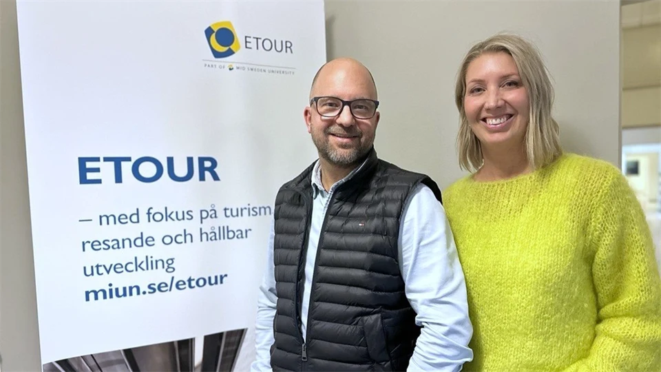 En man och en kvinna står framför en roll-up och ler