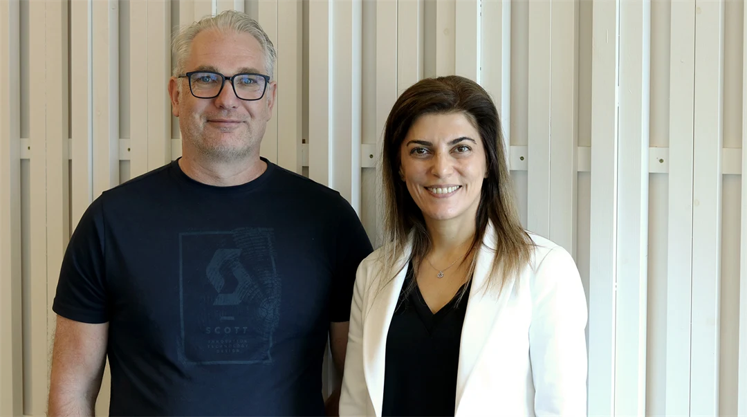 Professor Mikael Gidlund and Professor Sinem Coleri standing together in front of a light wooden wall during her visit to Mid Sweden University.