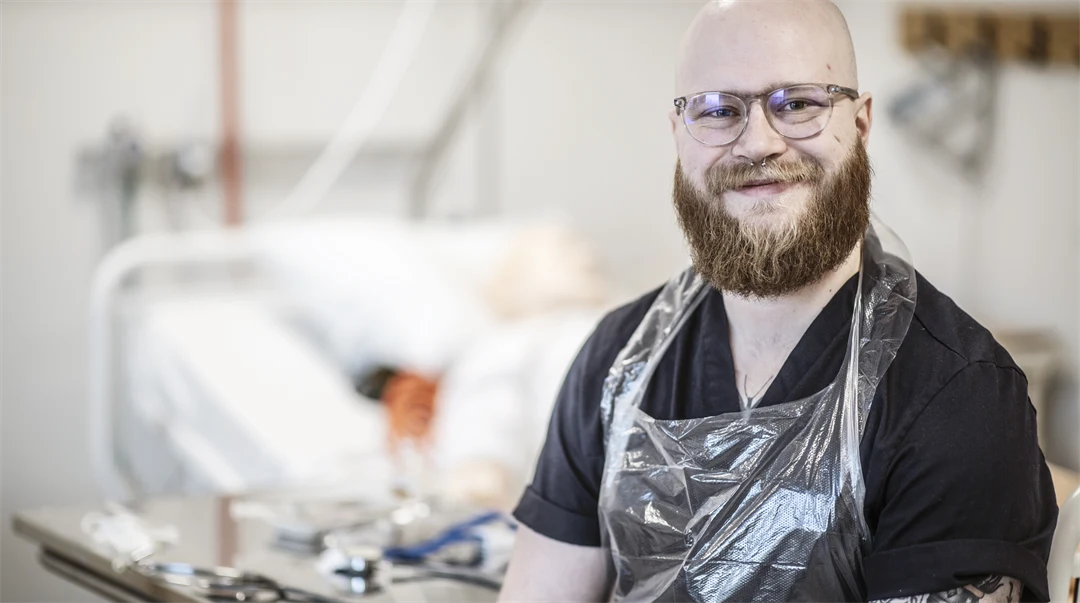 En man med skägg är i en sjukhusmiljö.