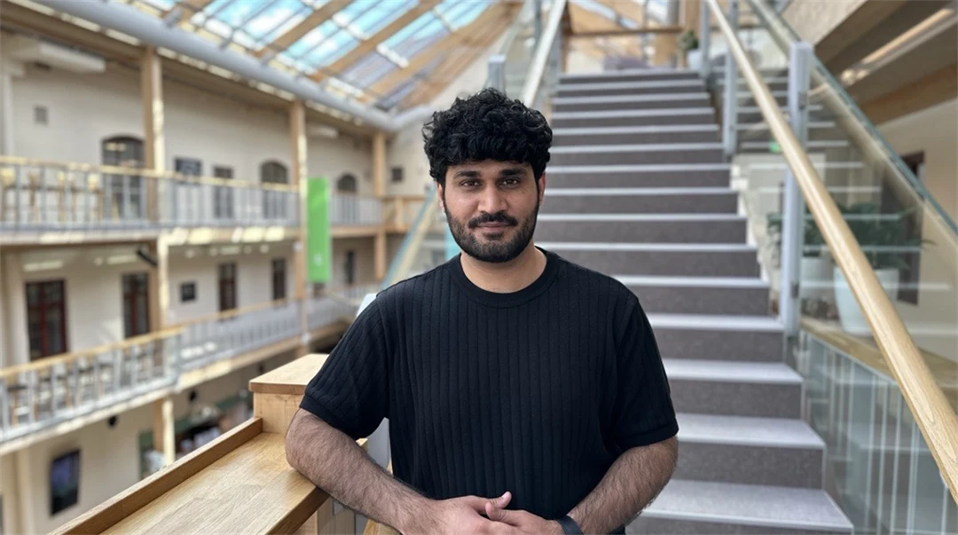 A man with short black hair and a black t-shirt