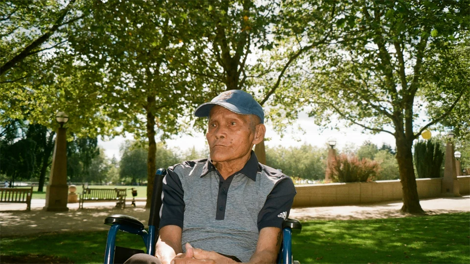 Äldre man i rullstol utomhus.