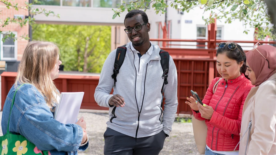 En grupp studenter som står och pratar med varandra utanför campus. 
