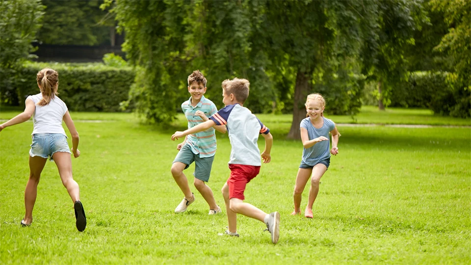 Happy kids running and playing game outdoors.