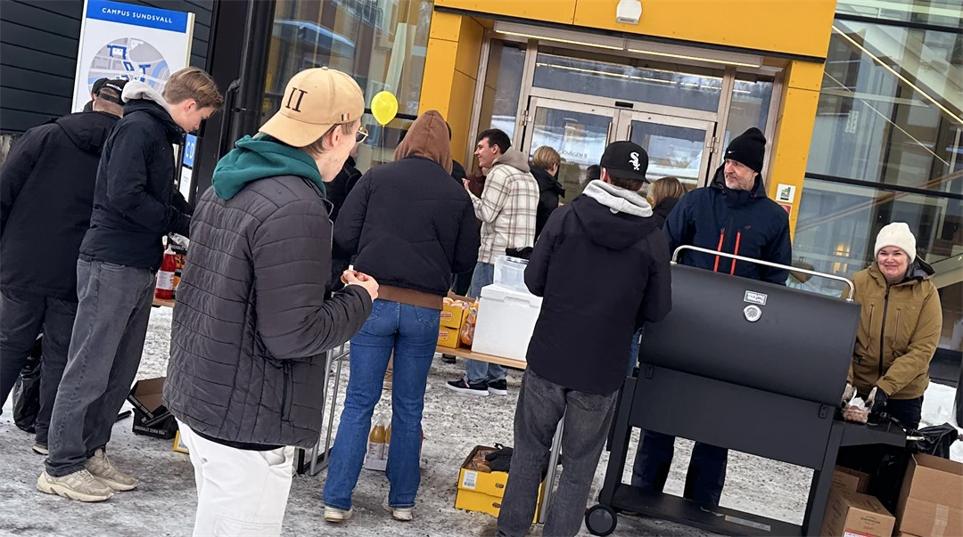 En grupp människor som står runt en grill